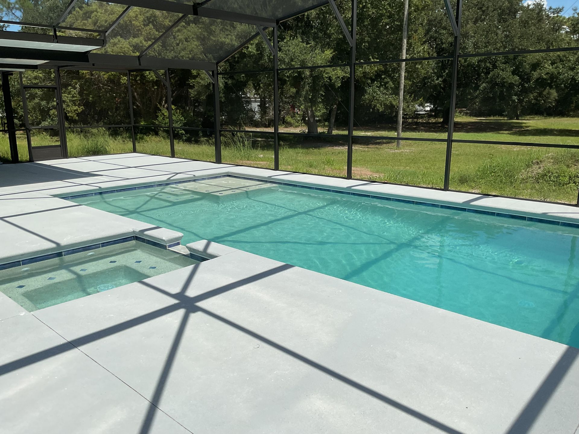 Screened backyard pool with turquoise water and white deck in sunlight