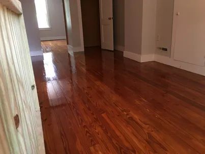 Empty hallway with polished hardwood floors and white walls.