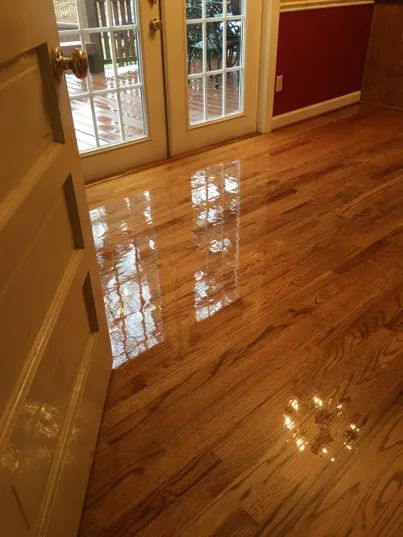 Shiny hardwood floor in an empty room with French doors and red accent walls