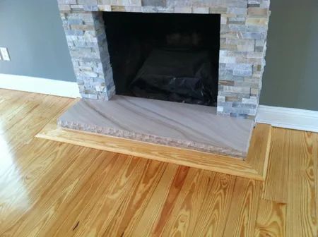 Stone fireplace with a beige hearth cover over a light wood floor in an empty room