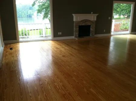 Empty living room with hardwood floors, dark walls, a fireplace, and large windows and patio door.
