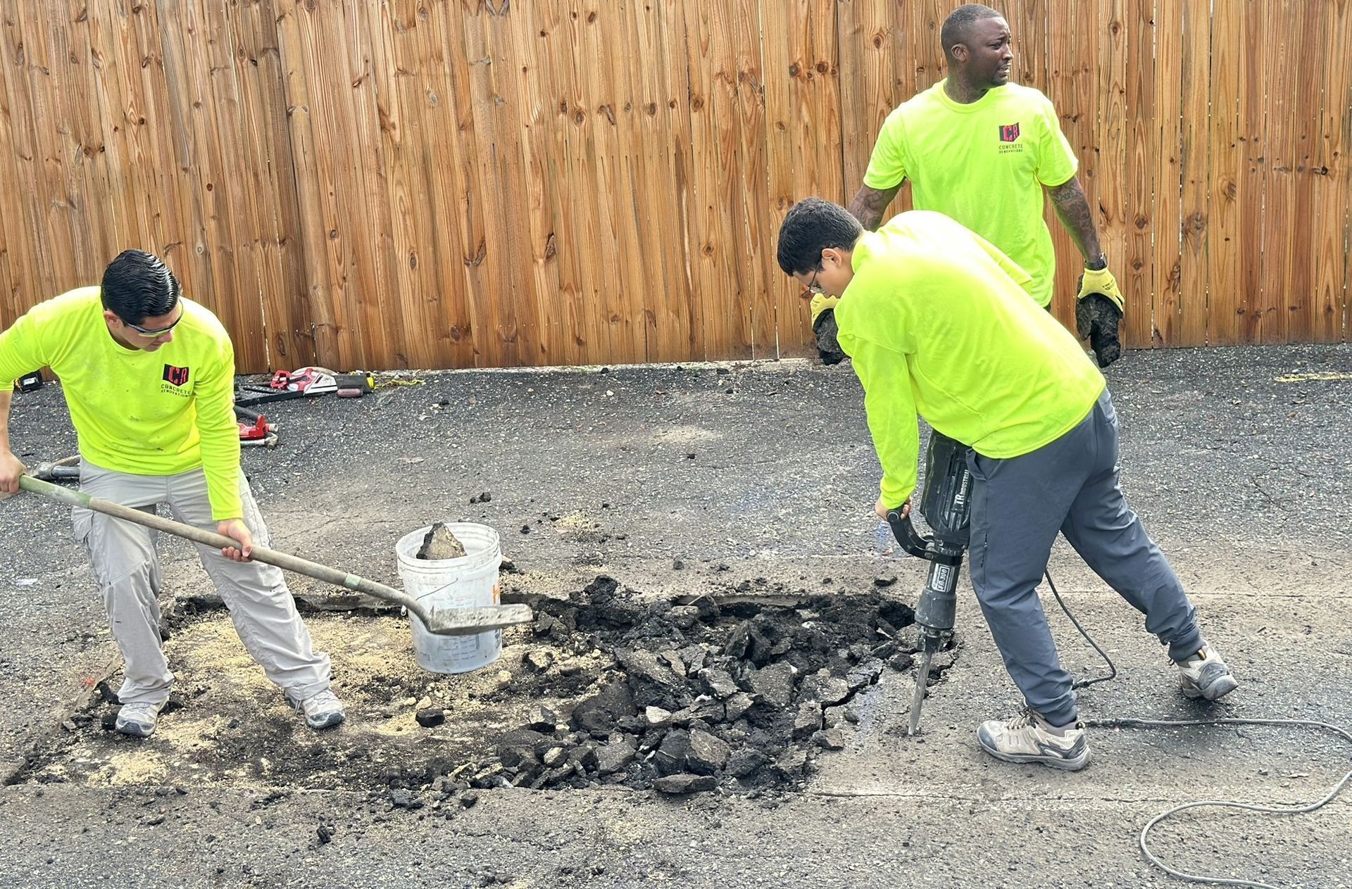 Person in safety gear smoothing fresh concrete with a trowel at a construction site.