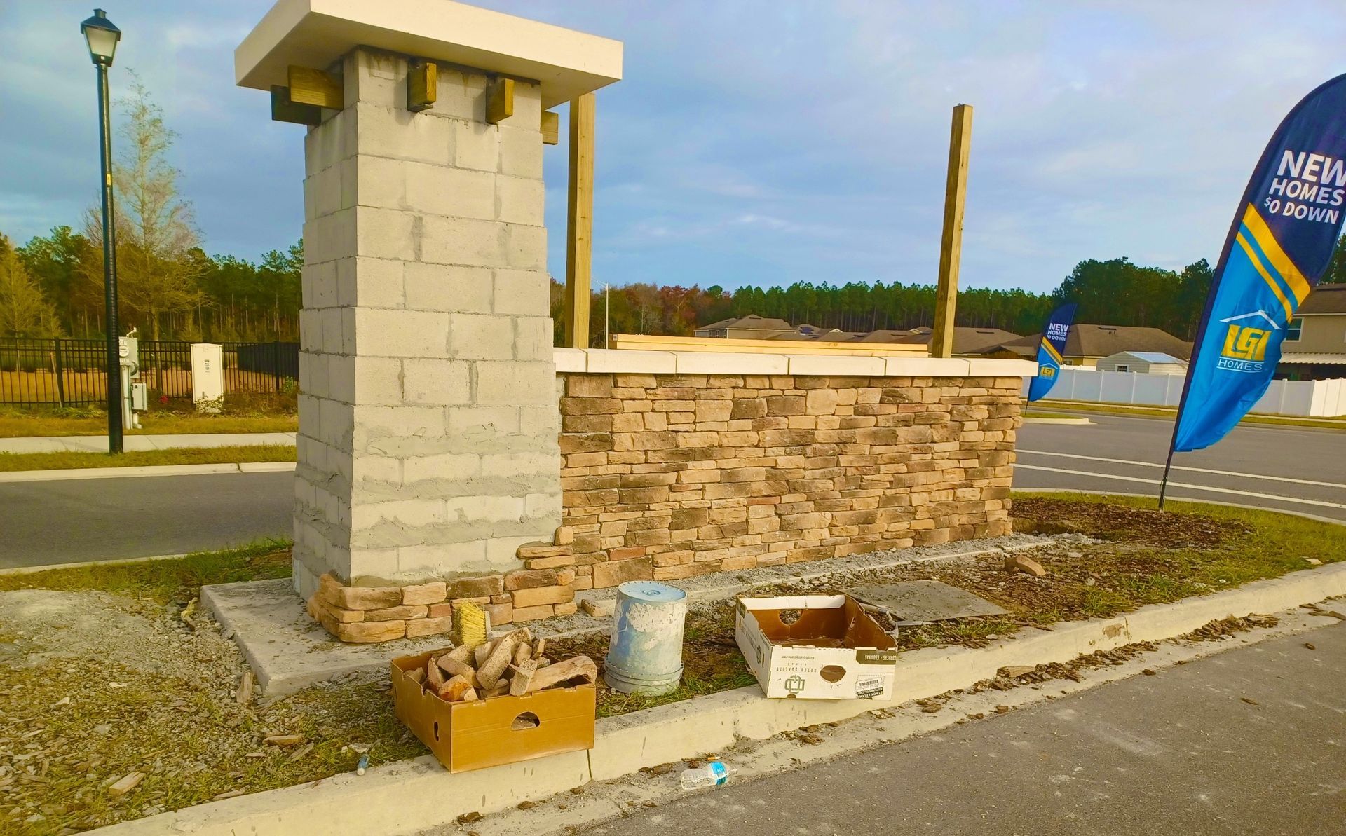 A brick pillar is being built on the side of the road