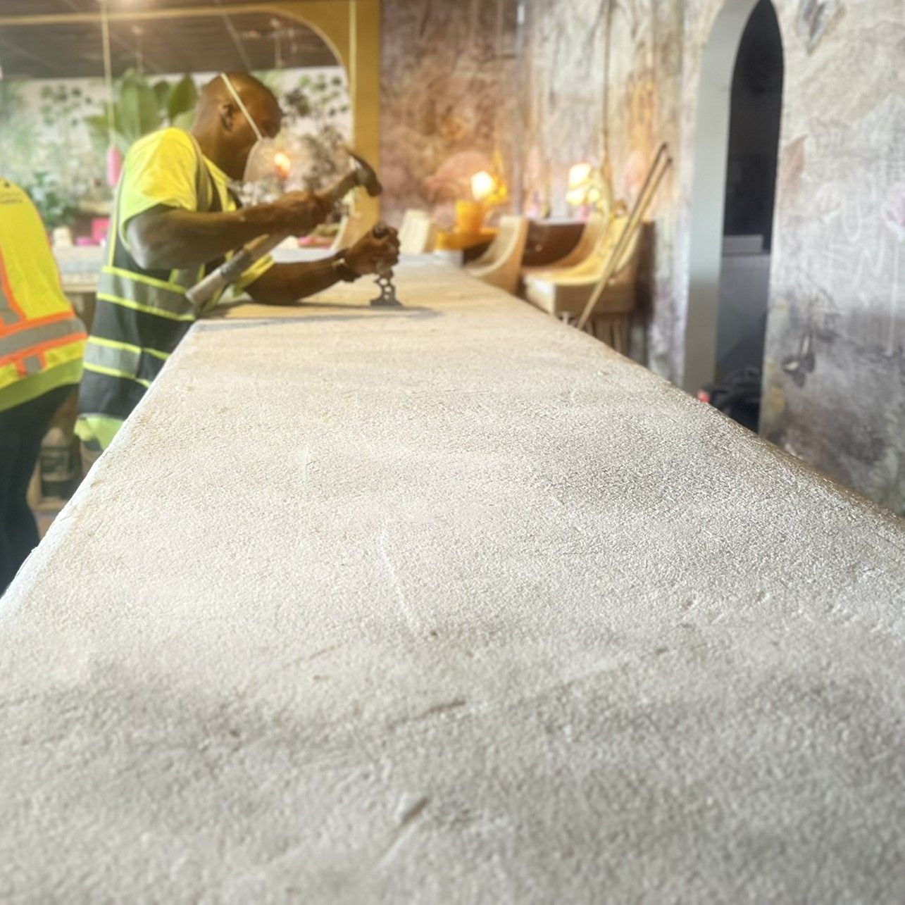 Workers in safety vests smoothing a large concrete bar top at restaurant