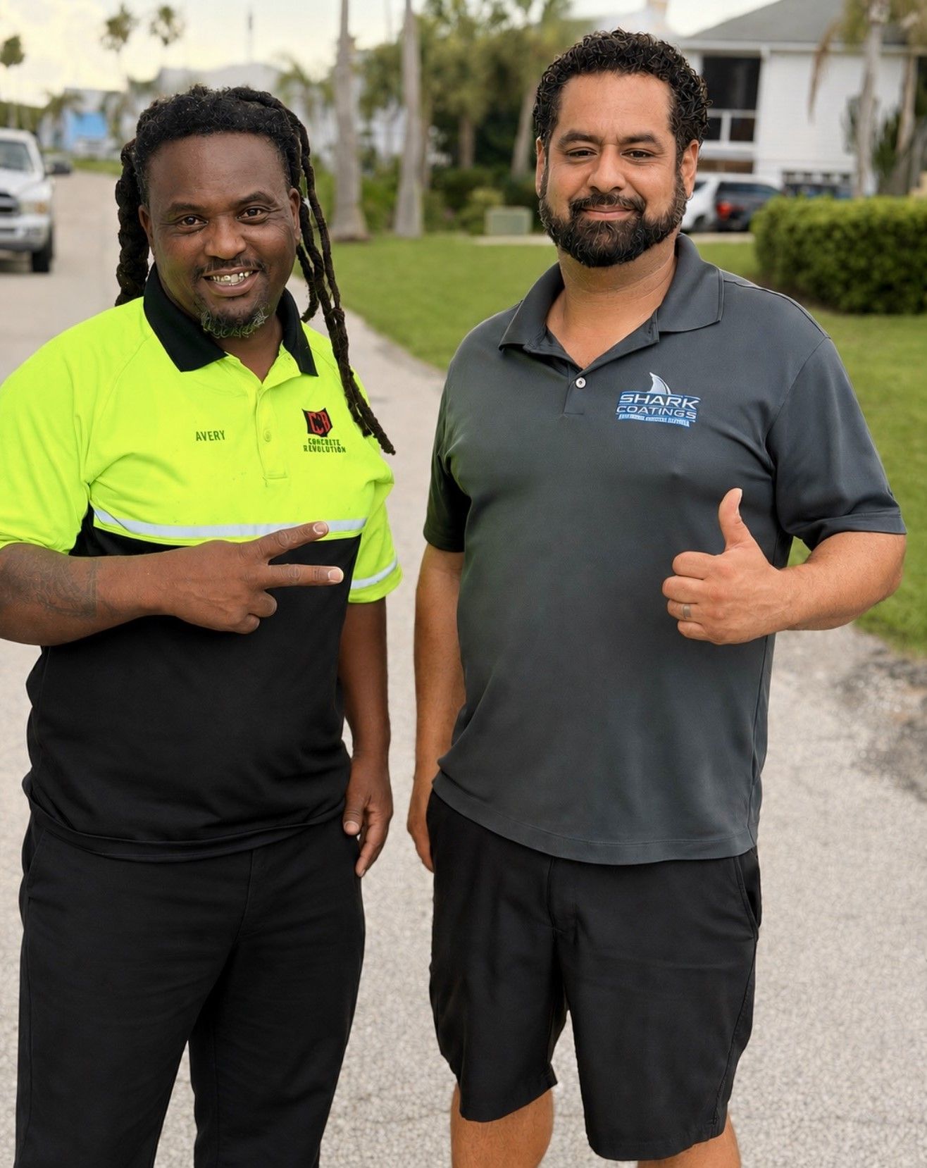 Two men standing outdoors, smiling and giving thumbs up, one in a neon green shirt and one in a gray polo.