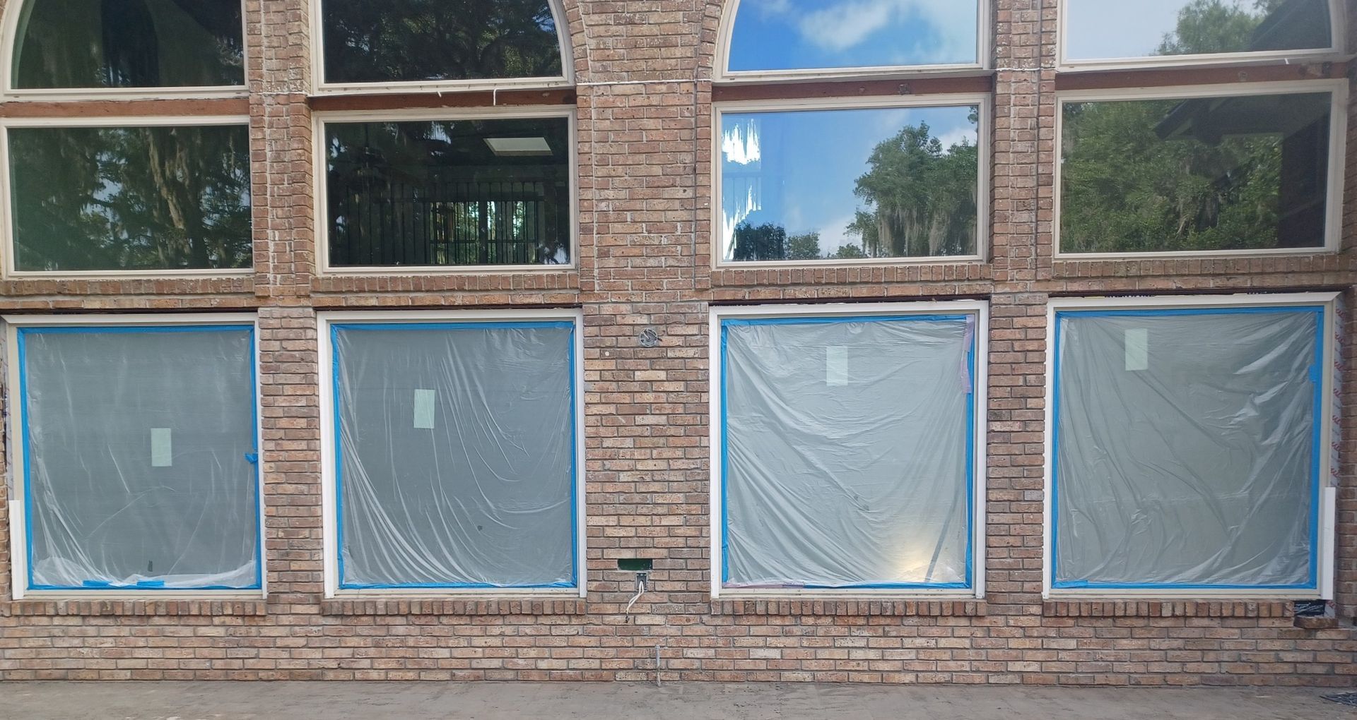 A brick building with a lot of windows covered in plastic.