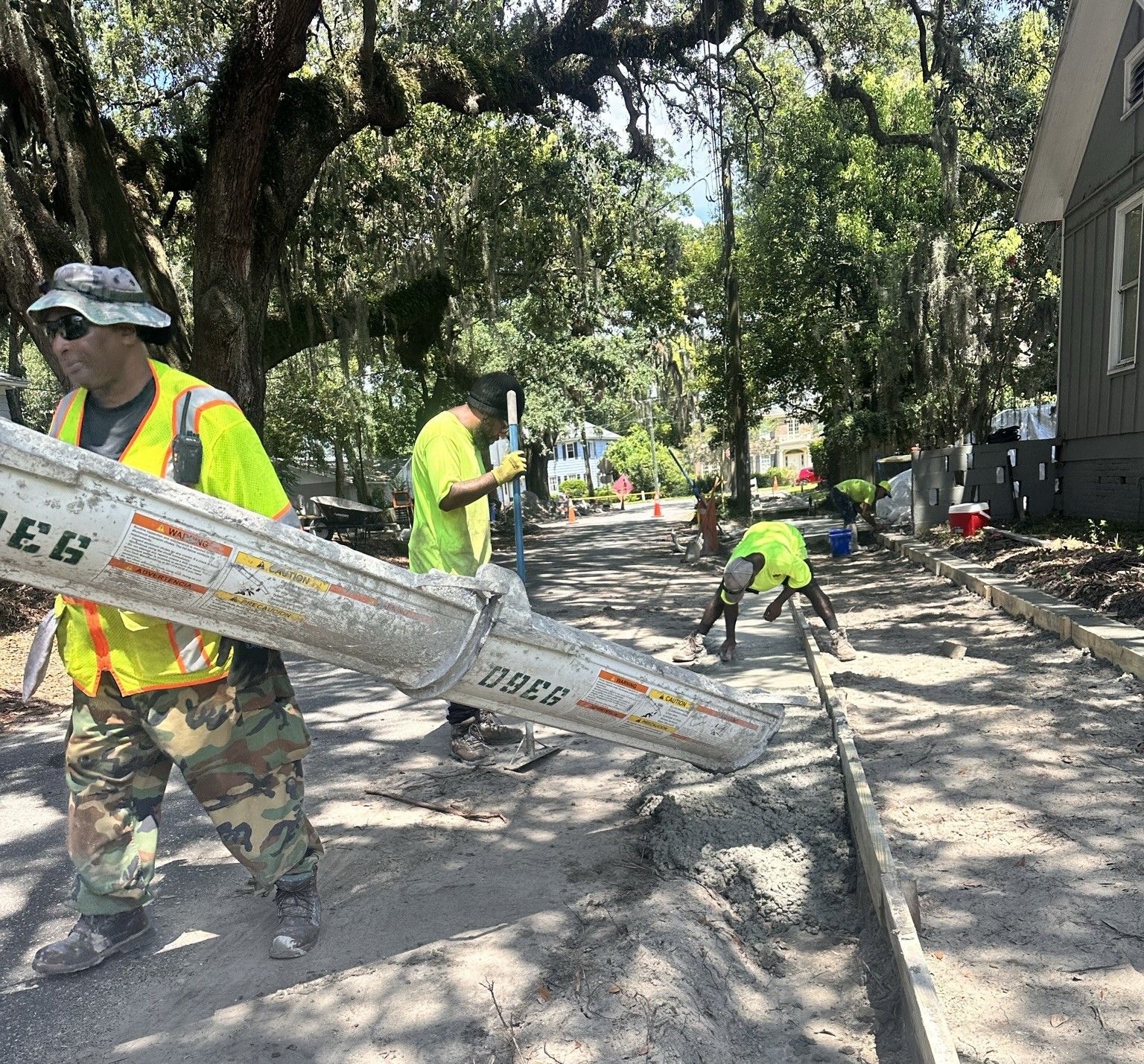 A group of construction workers are concrete finishing on a street.