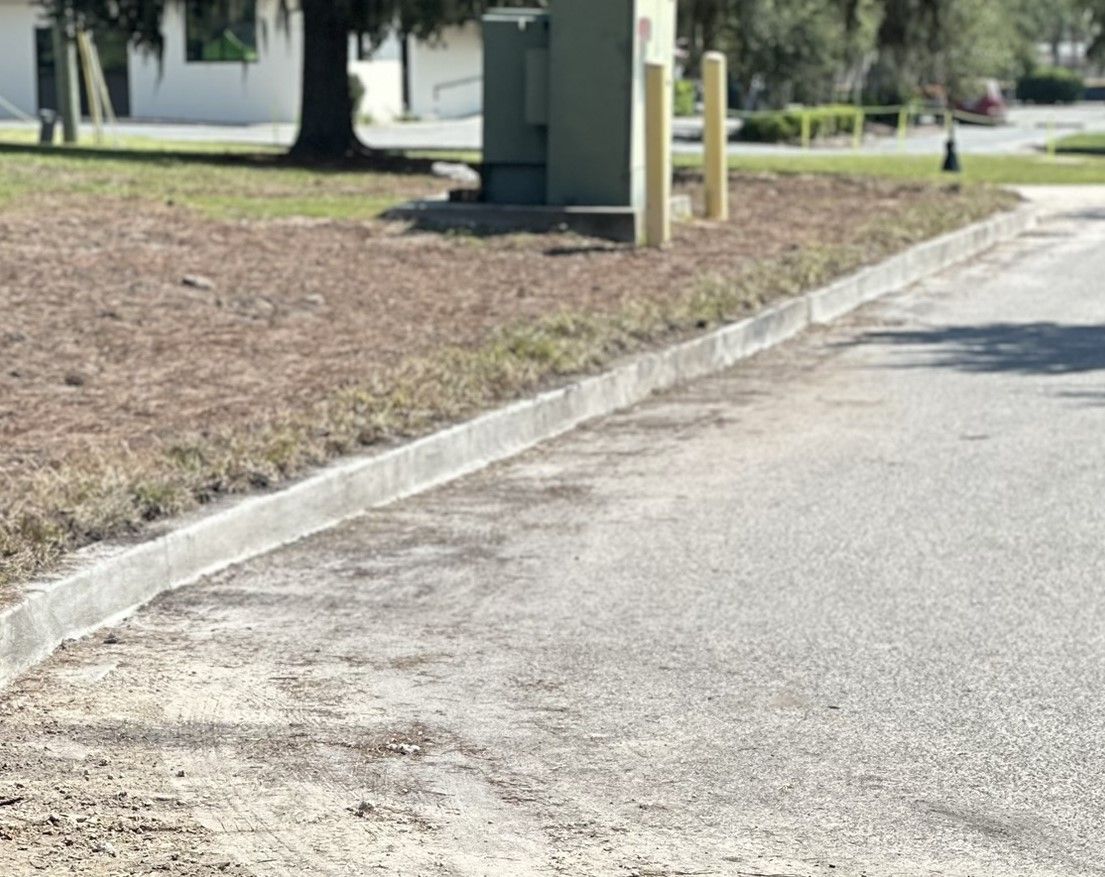 A street with a  concrete curb and grass on the side of it.
