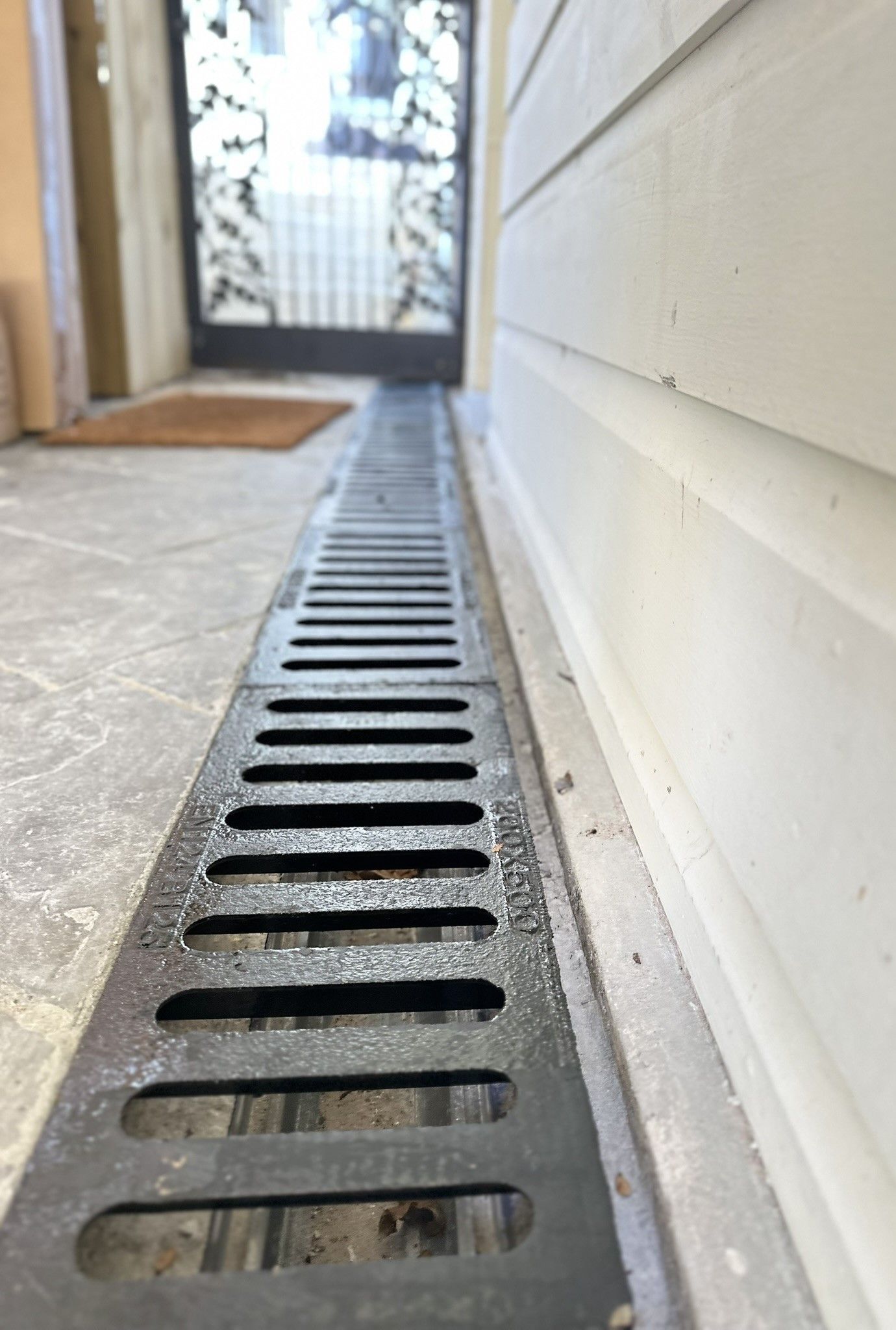A drain on the side of a building next to a door.