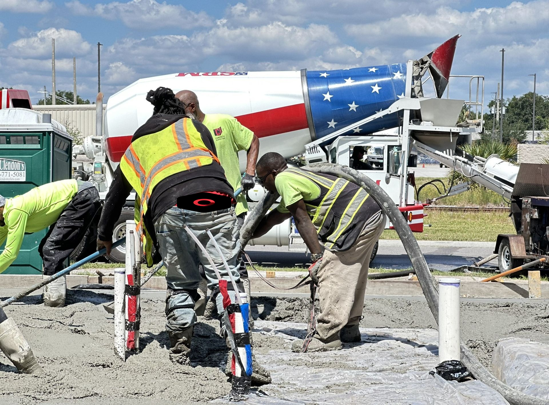 Workers in safety pouring concrete and finishing at a construction site.