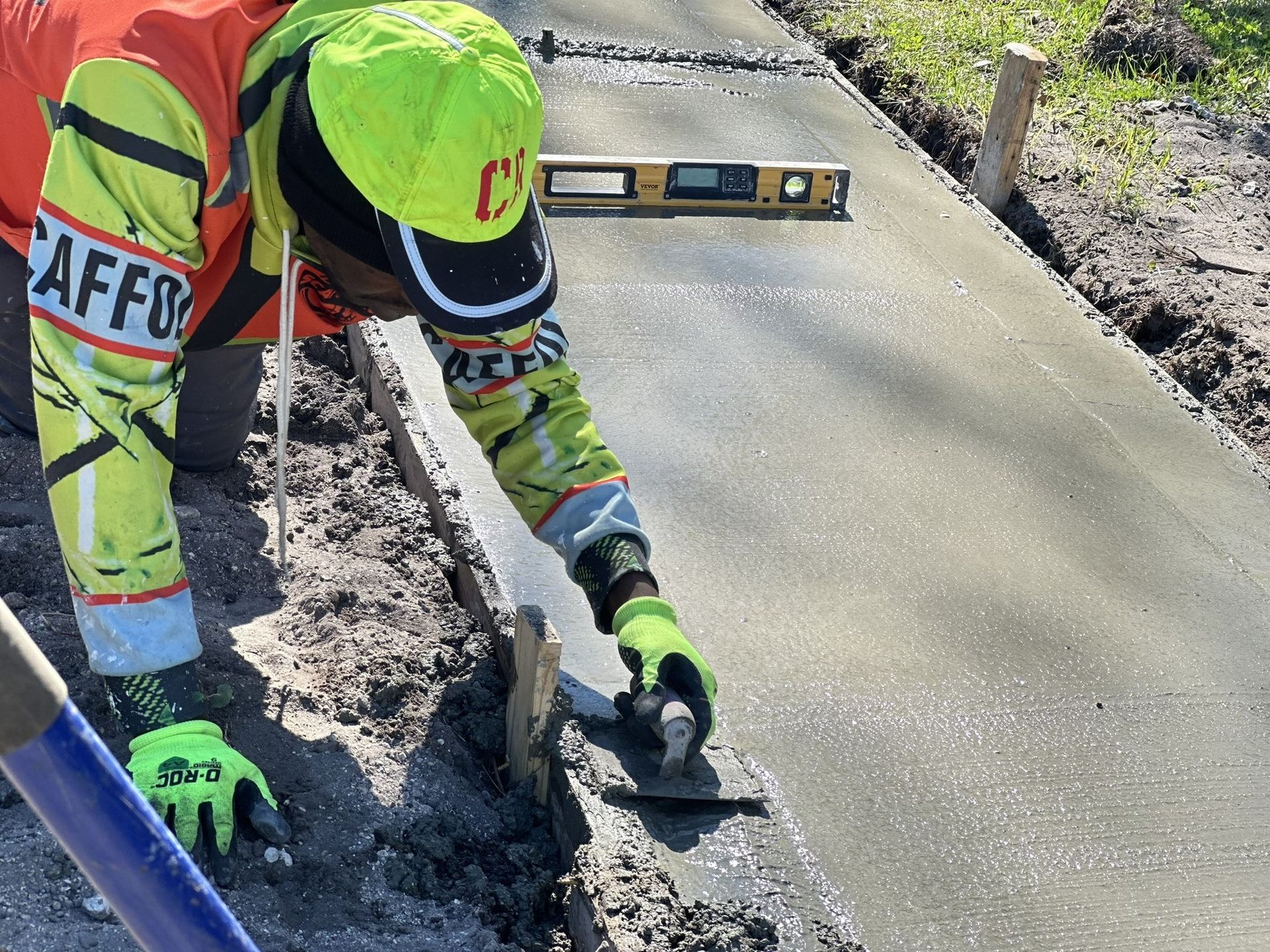 A construction worker is using a trowel on a concrete surface.