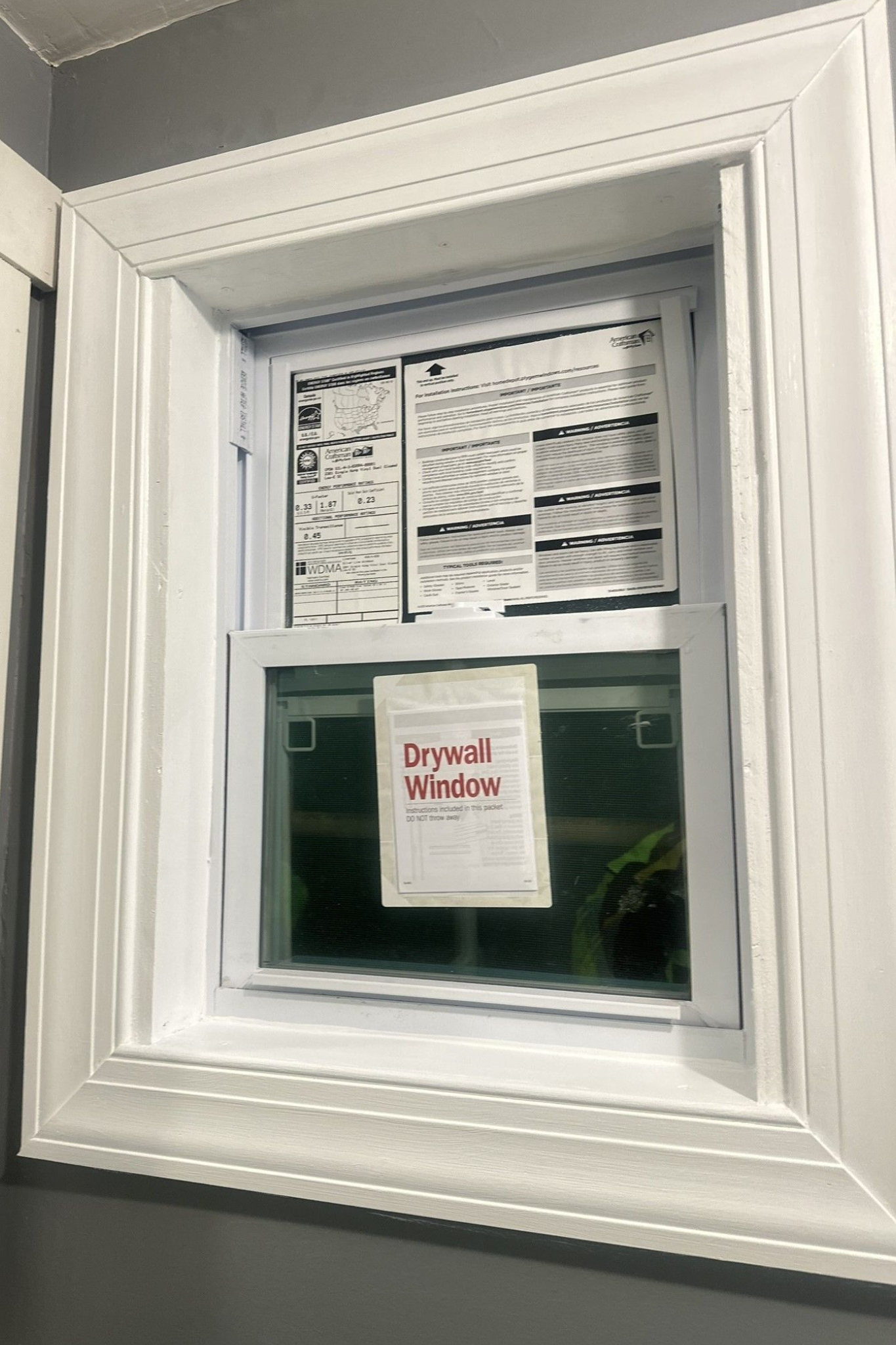 Small window with white trim and a red notice posted on the glass