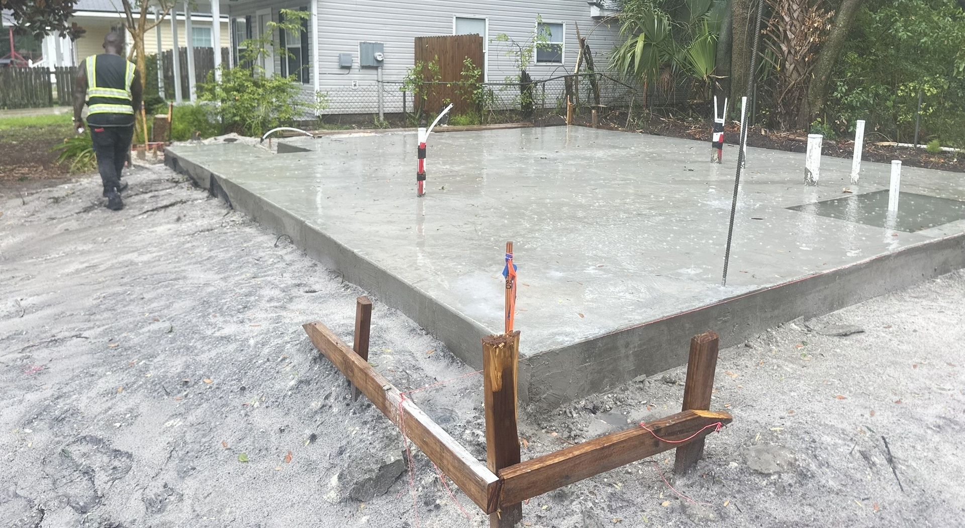Freshly poured concrete slab at a construction site with forms and support stakes