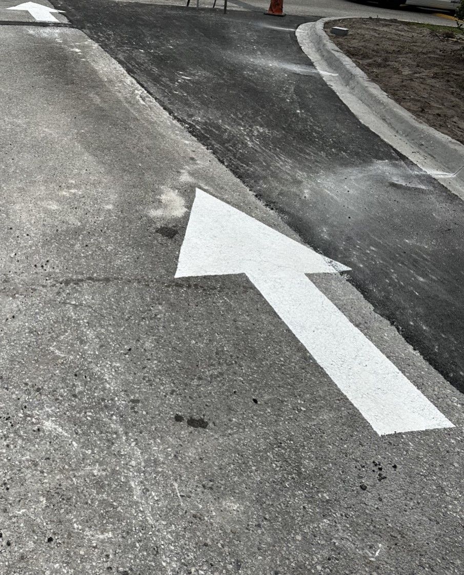A white arrow is painted on asphalt