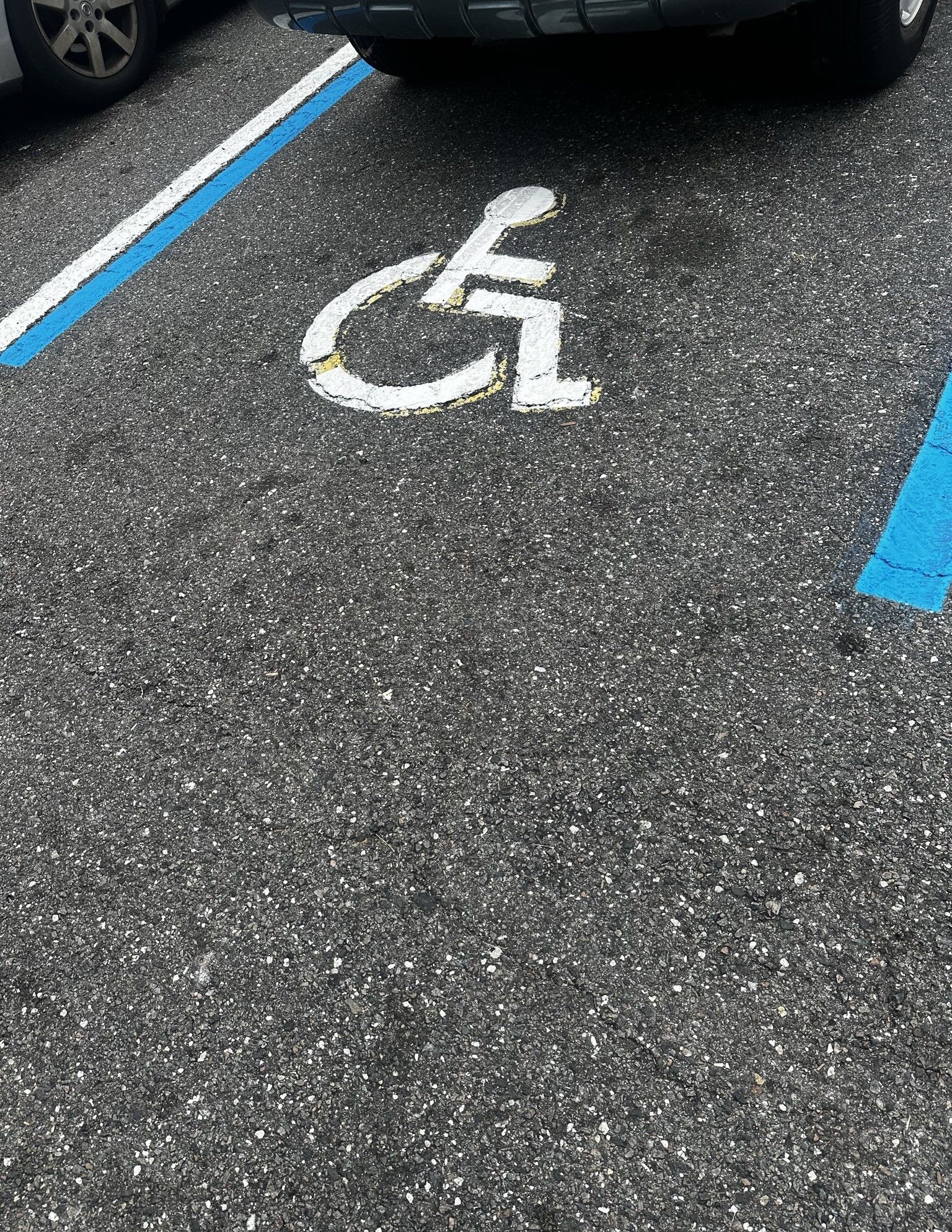 A handicap sign is painted on the ground in a parking lot.