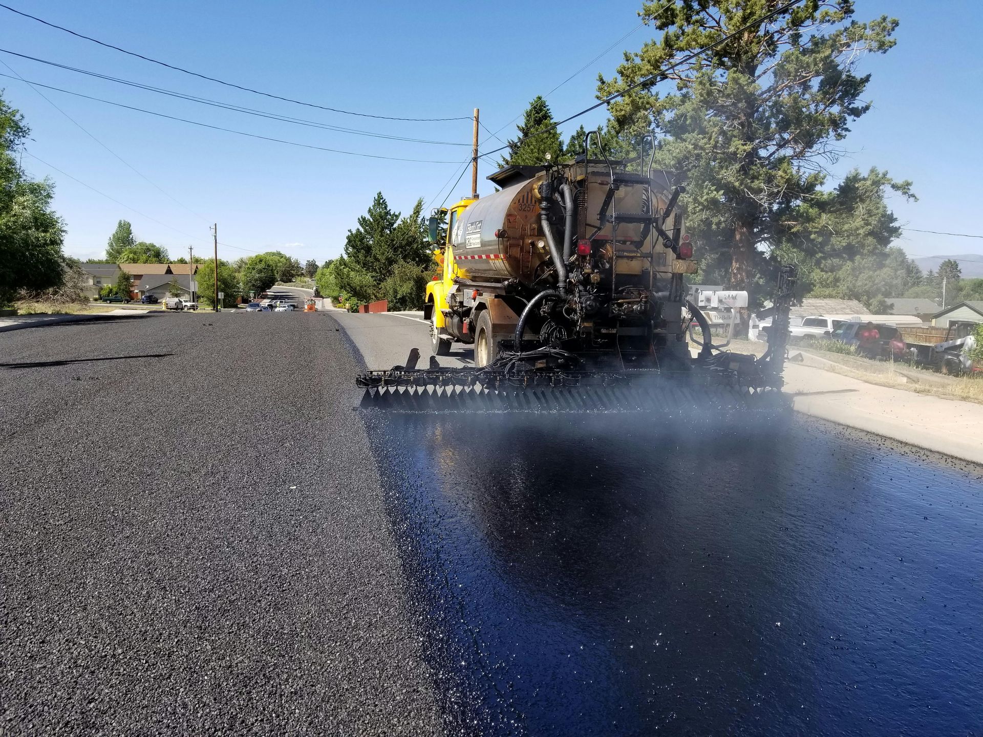 Asphalt truck spraying fresh seal coating onto pavement