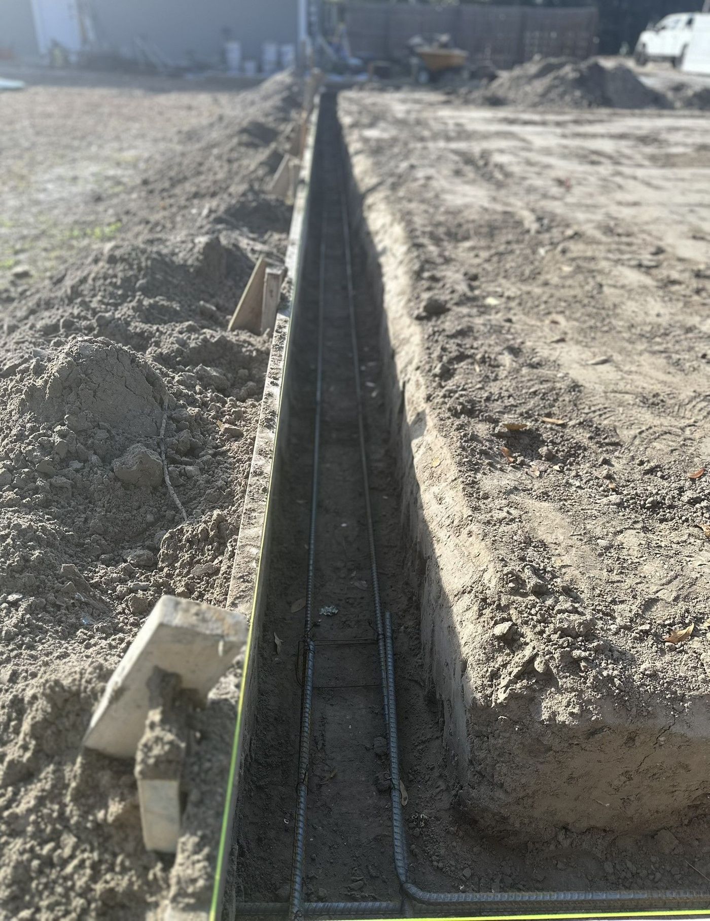 Concrete foundation trench with rebar and dirt piles on a construction site