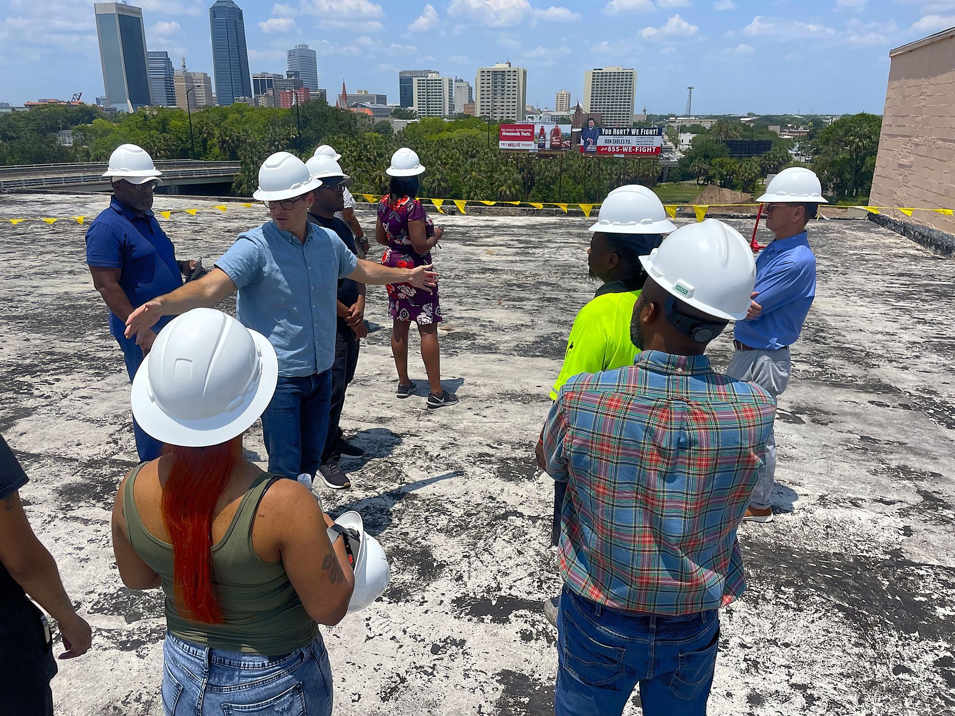 People in hard hats gather on a rooftop, with a city skyline in the background.