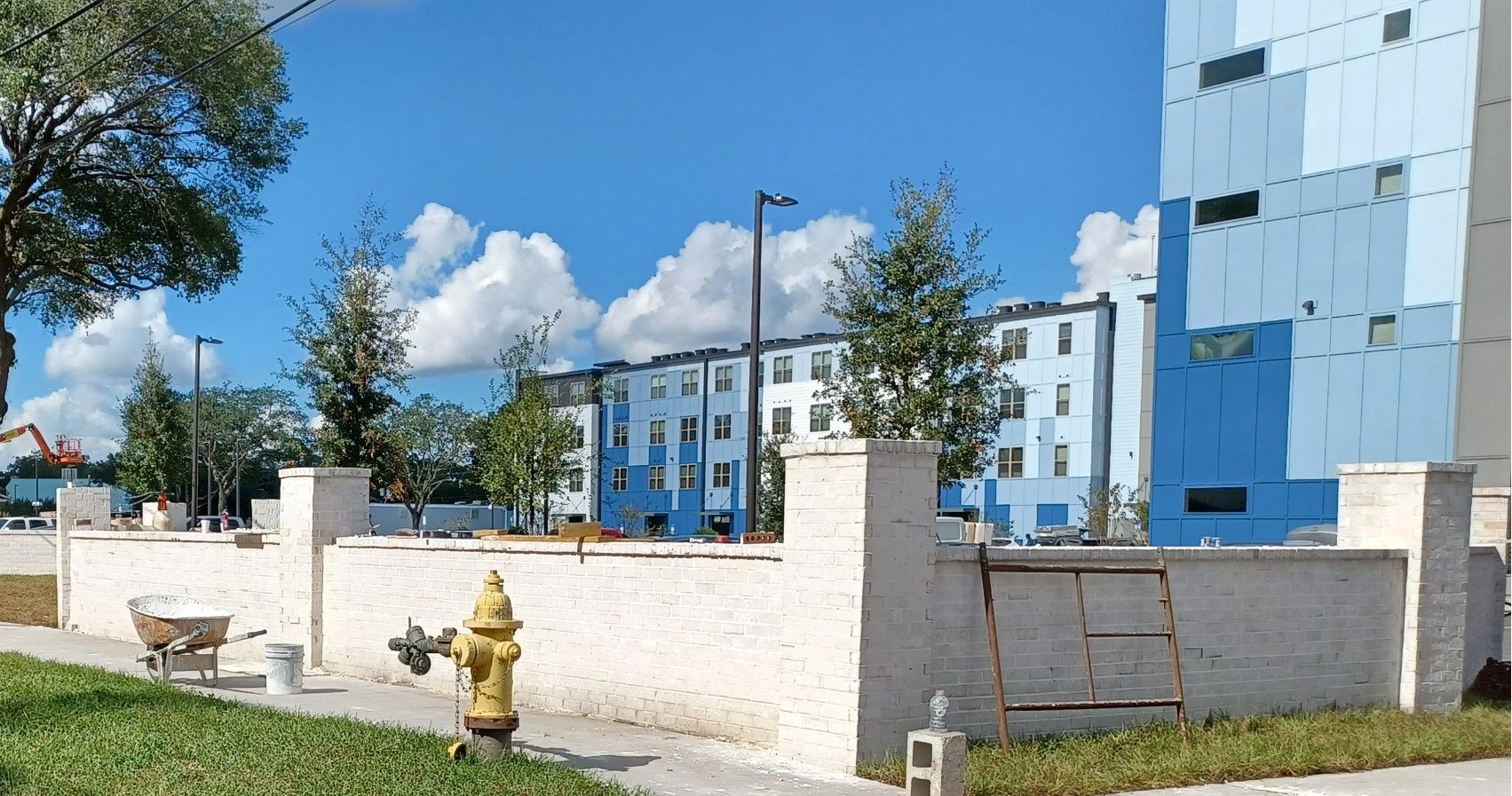 A fire hydrant in front of a white Brick wall with a blue building in the background