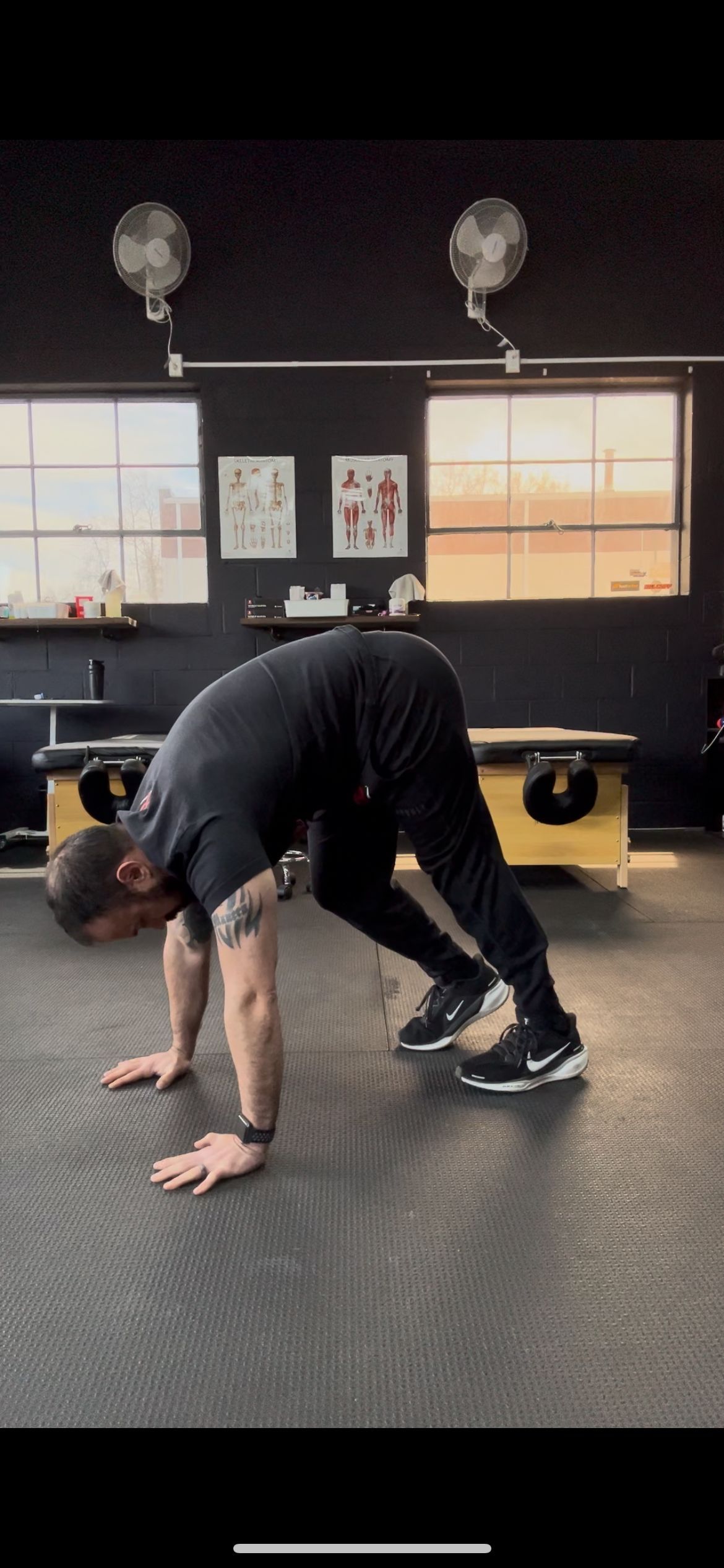 A man is doing push ups on the floor in a gym.