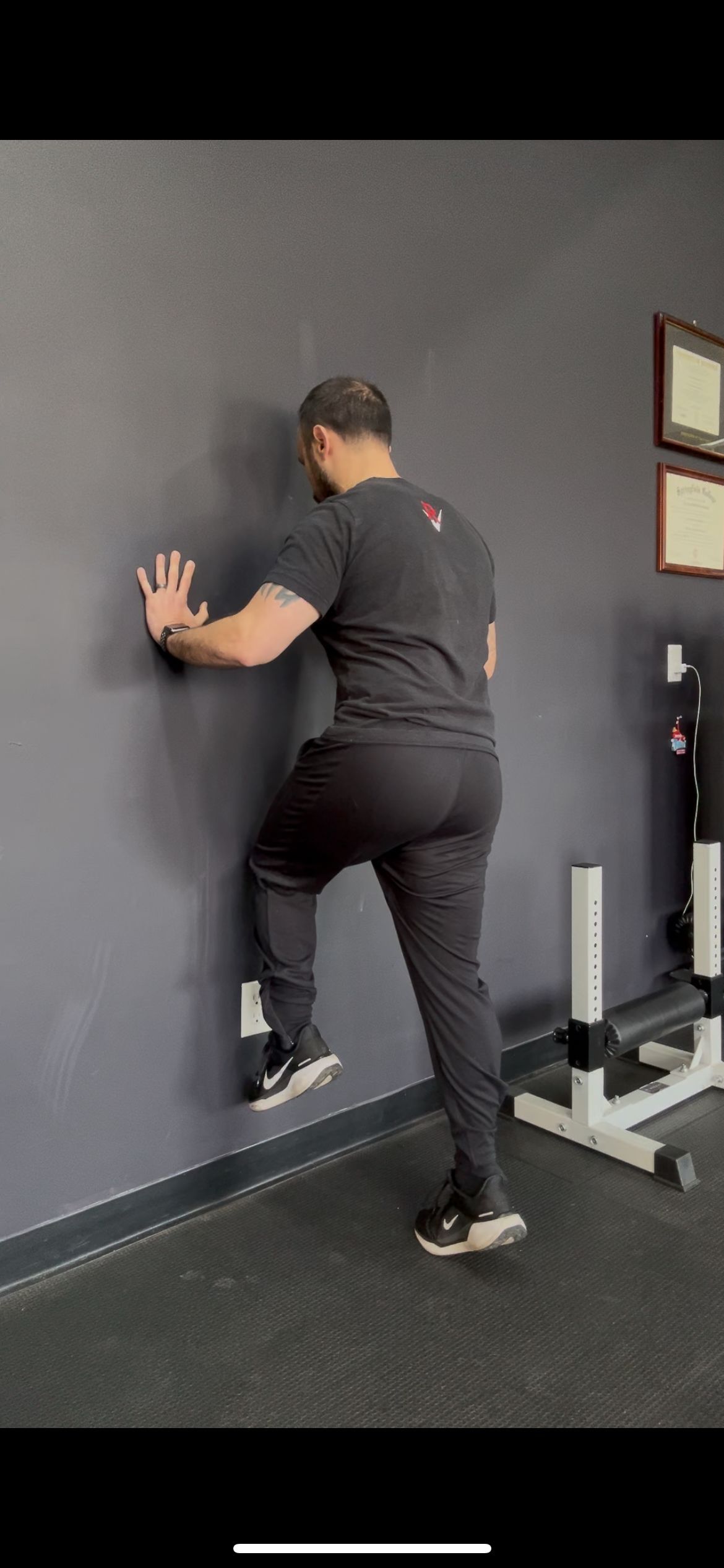A man is leaning against a wall in a gym.