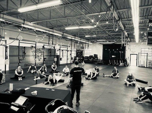 A man is standing in front of a group of people in a gym.