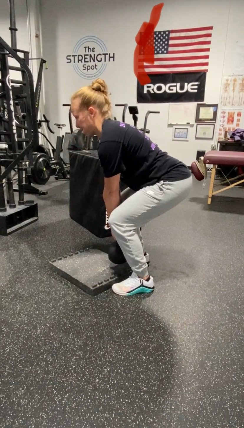 A woman is squatting with a barbell in a gym.