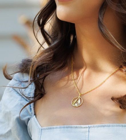 A close up of a woman wearing a necklace on her neck.
