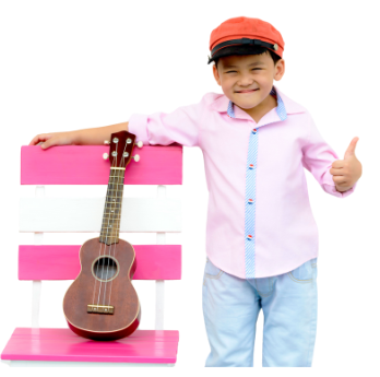 Smiling child in red cap standing beside a pink bench with a ukulele, giving a thumbs-up