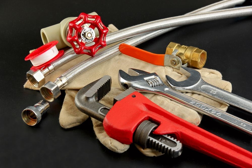 A Pair Of Plumbing Gloves Laying On Top Of A Wrench — Warrnambool Emergency Plumbing in Warrnambool, VIC