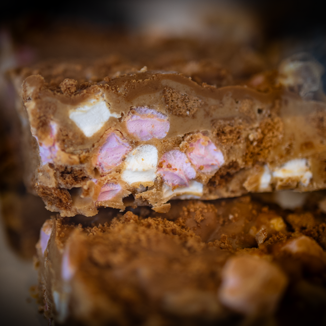 Rocky road squares with pink and white marshmallows, and bits of crumbly biscuit.