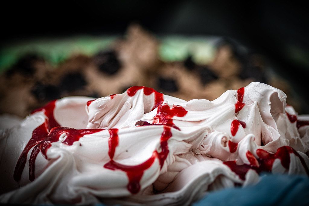 White ice cream with red sauce drizzled over it.