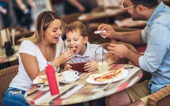 A family is sitting at a table in a restaurant eating food.