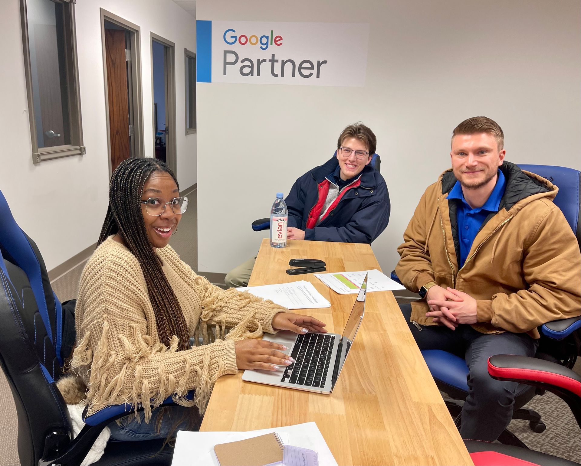 SEO Content Writing Service: Three people meeting at a desk in a Google Partner office, smiling at the camera.