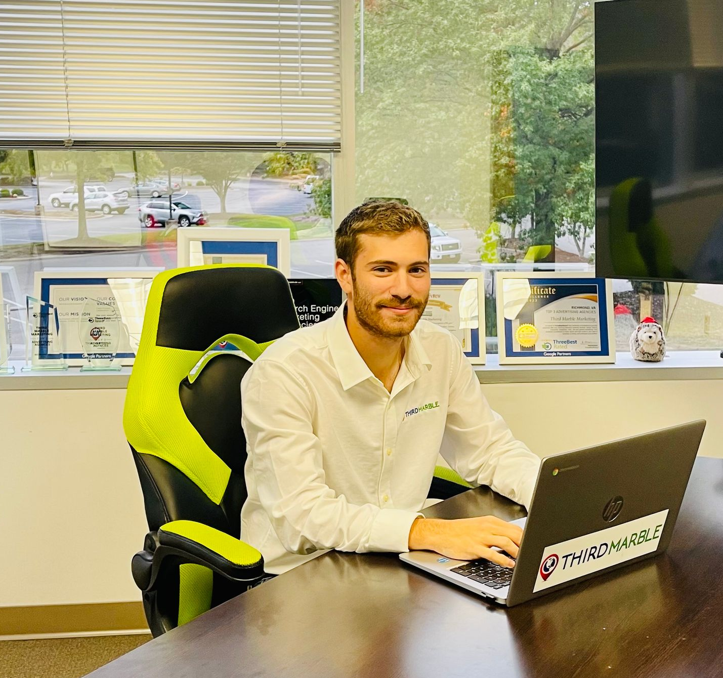 SEO Content Writing Service: Man sitting at a conference table using a laptop in a bright office with large windows.