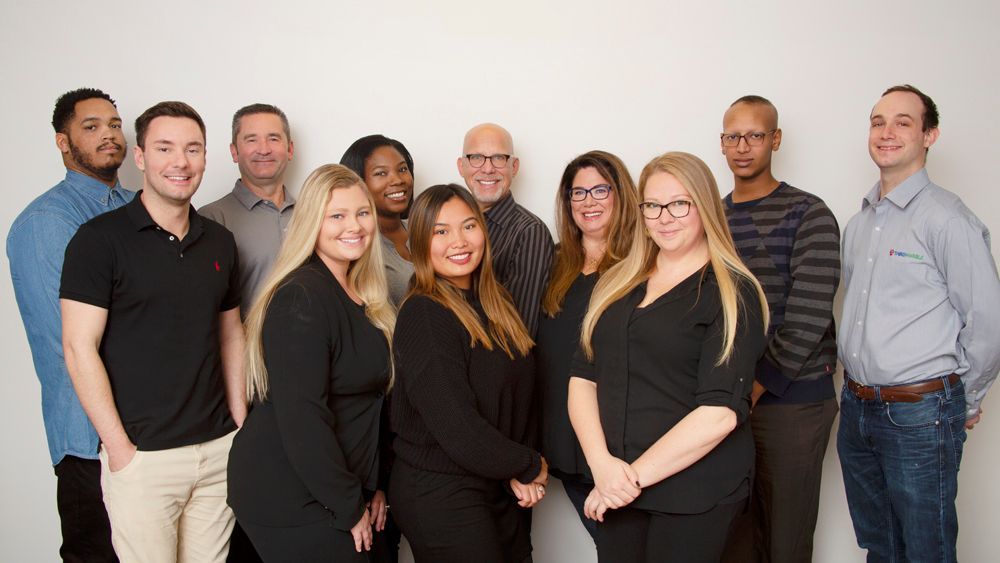 Premier SEO & AI Package: Group of nine people standing together indoors, smiling at the camera against a plain white background.