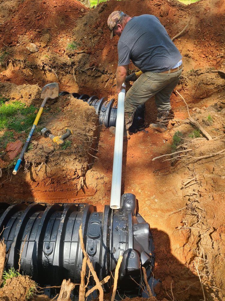 A man is working on a septic tank in the dirt.