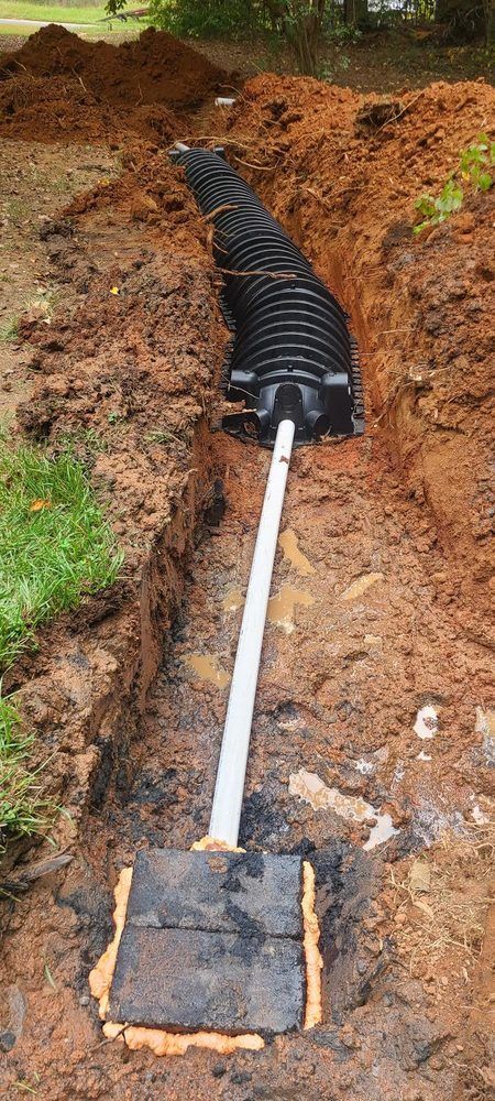 A septic system is being installed in a dirt trench.