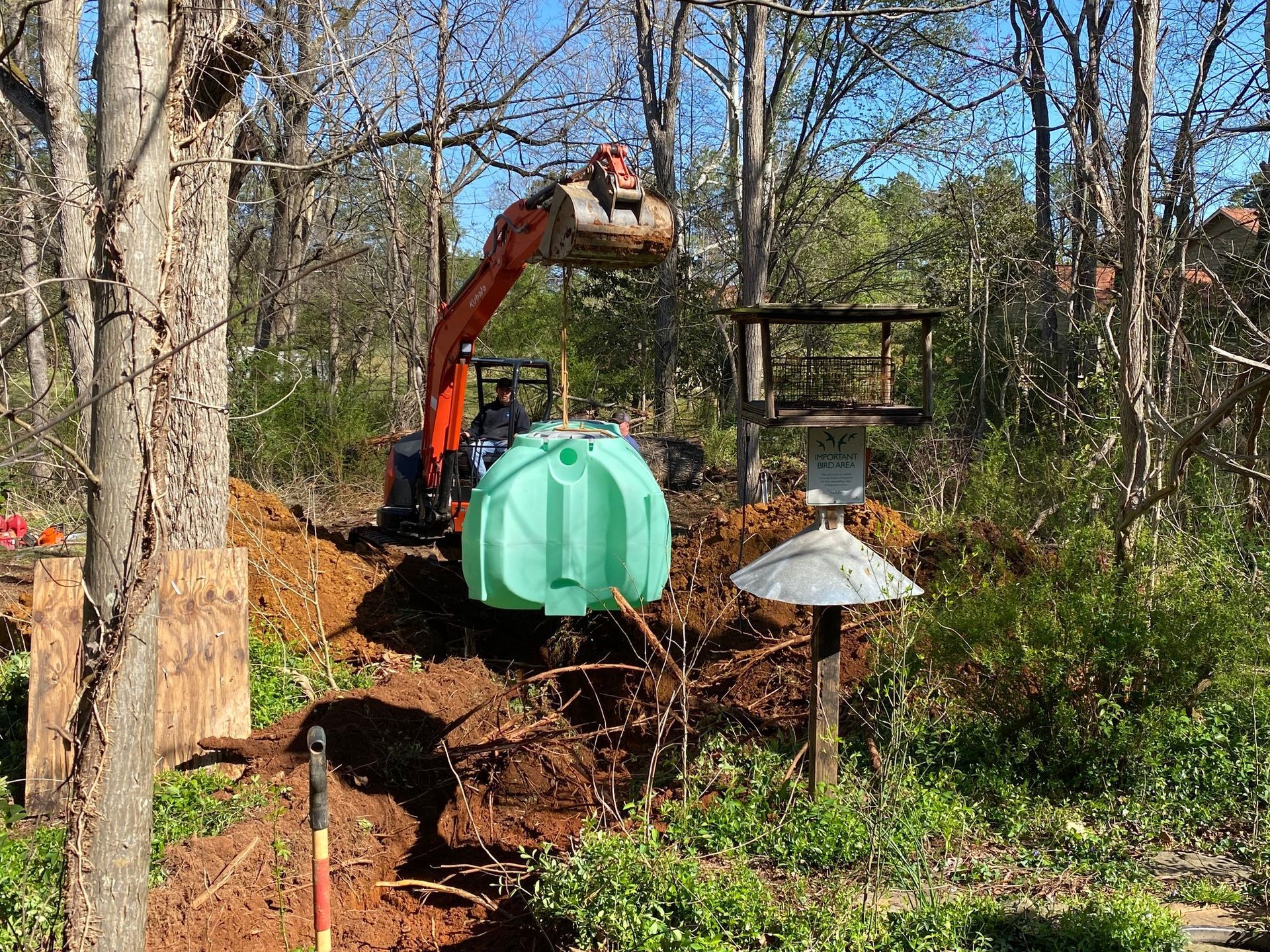An excavator is digging a hole in the ground to install a septic tank.