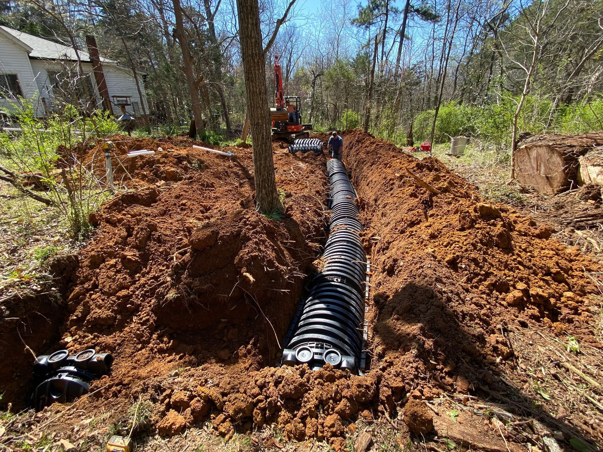 A large pipe is being installed in the dirt in a yard.