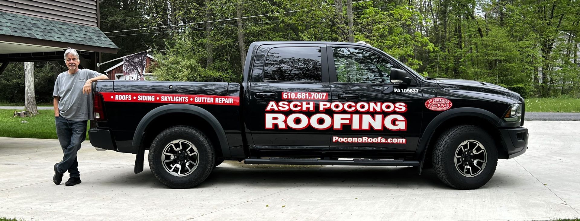 A man is standing next to a truck that says arch pocono roofing.