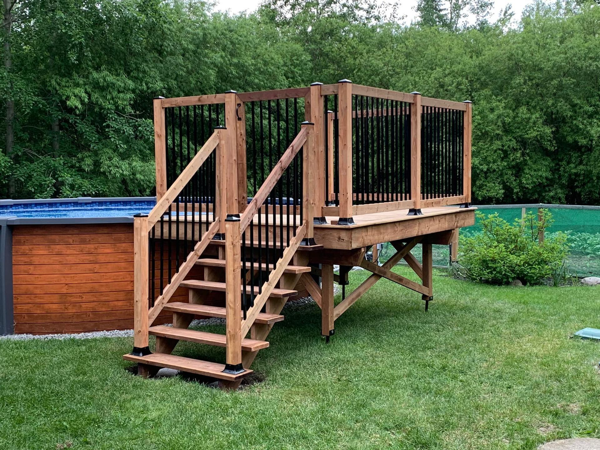 Une terrasse en bois avec des escaliers à côté d'une piscine.