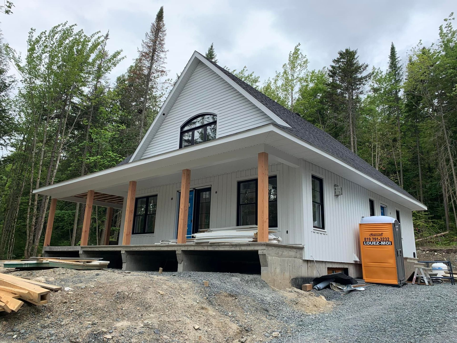 Une maison blanche est en construction au milieu d'une forêt.