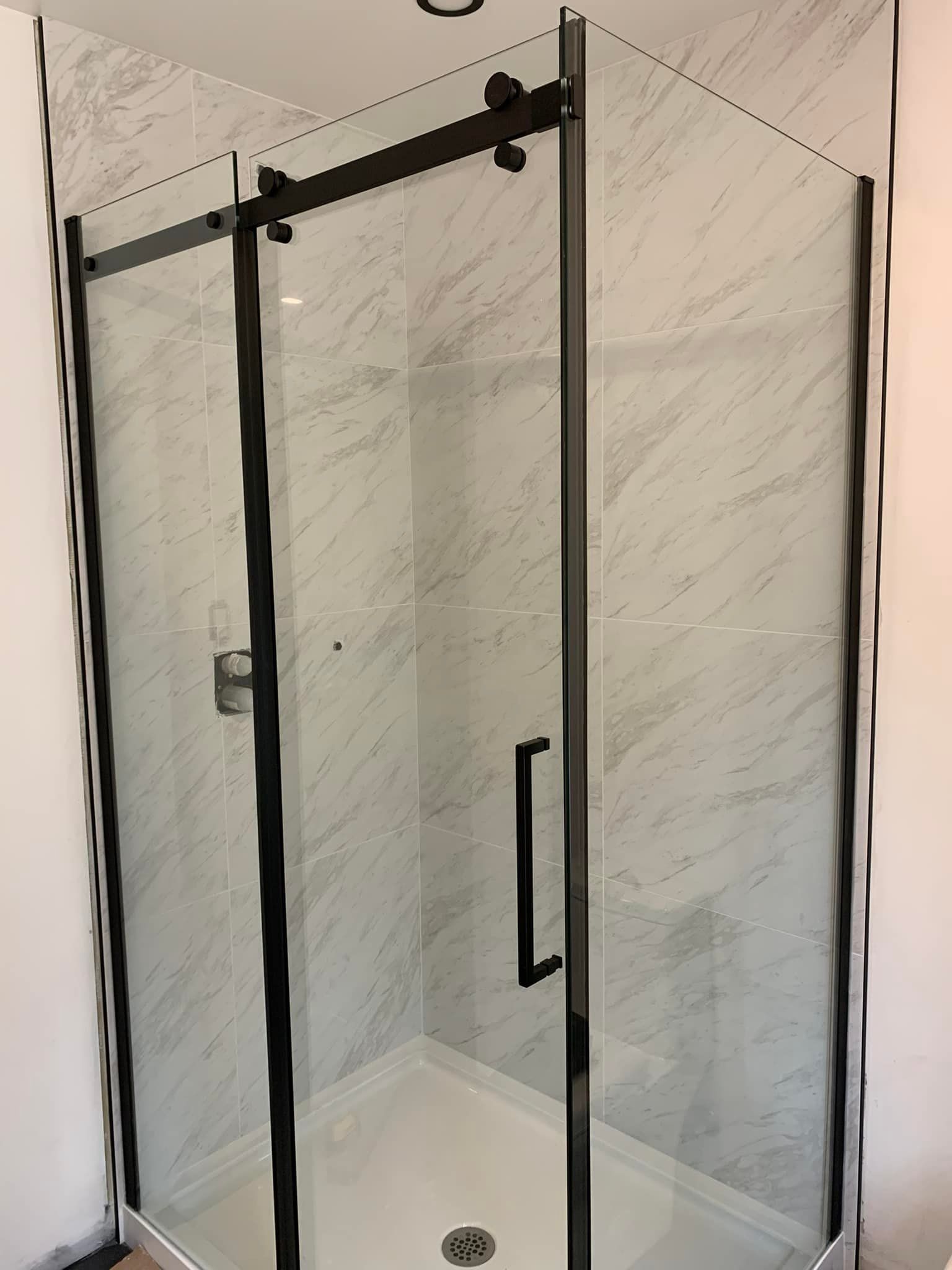 Une cabine de douche avec une porte coulissante en verre dans une salle de bain.