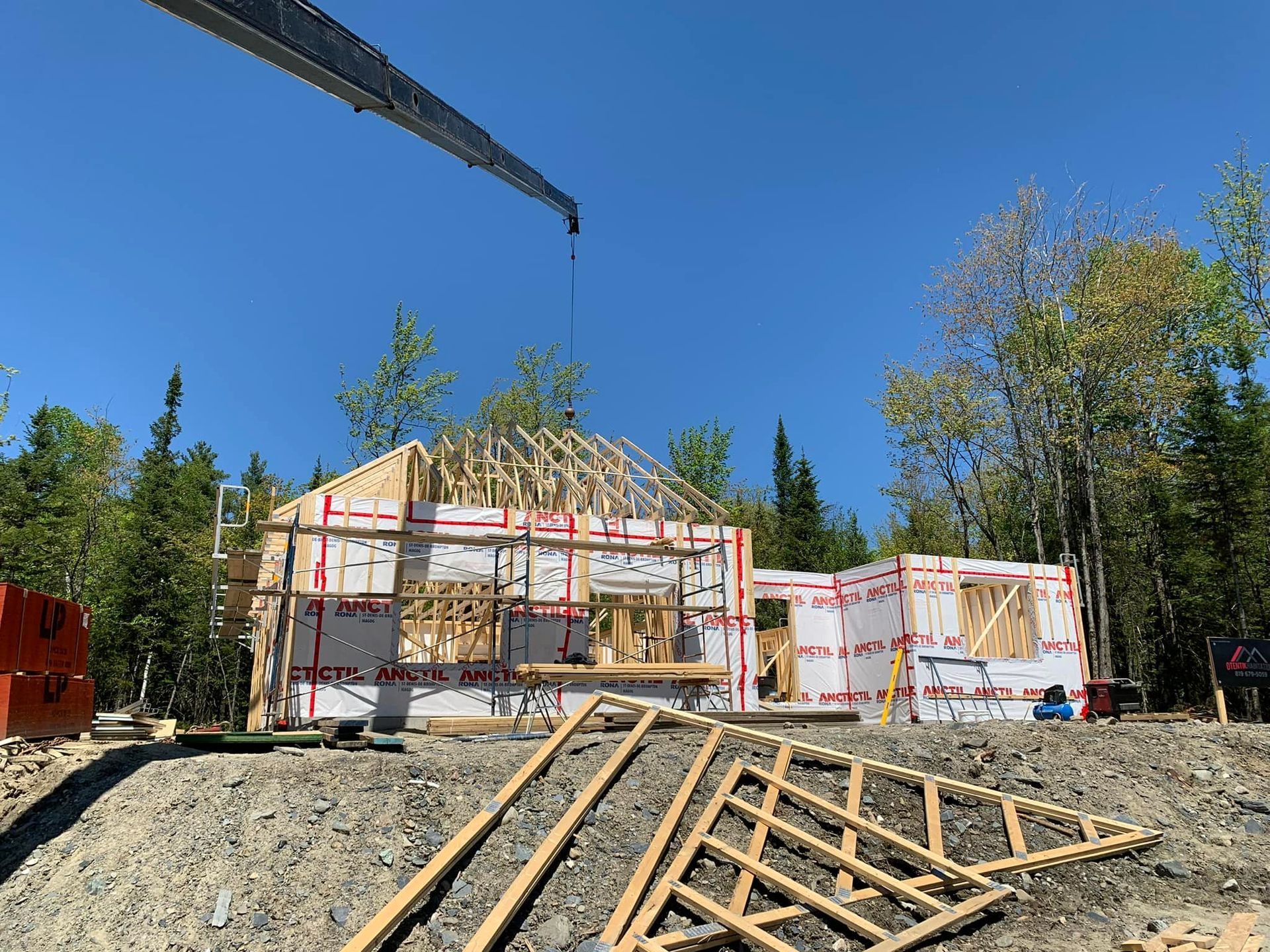 Une grue soulève le toit d'une maison en construction.