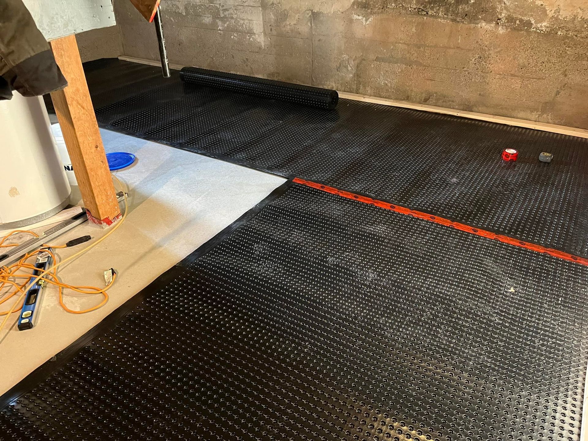 Une personne pose un tapis noir sur le sol d'une pièce.