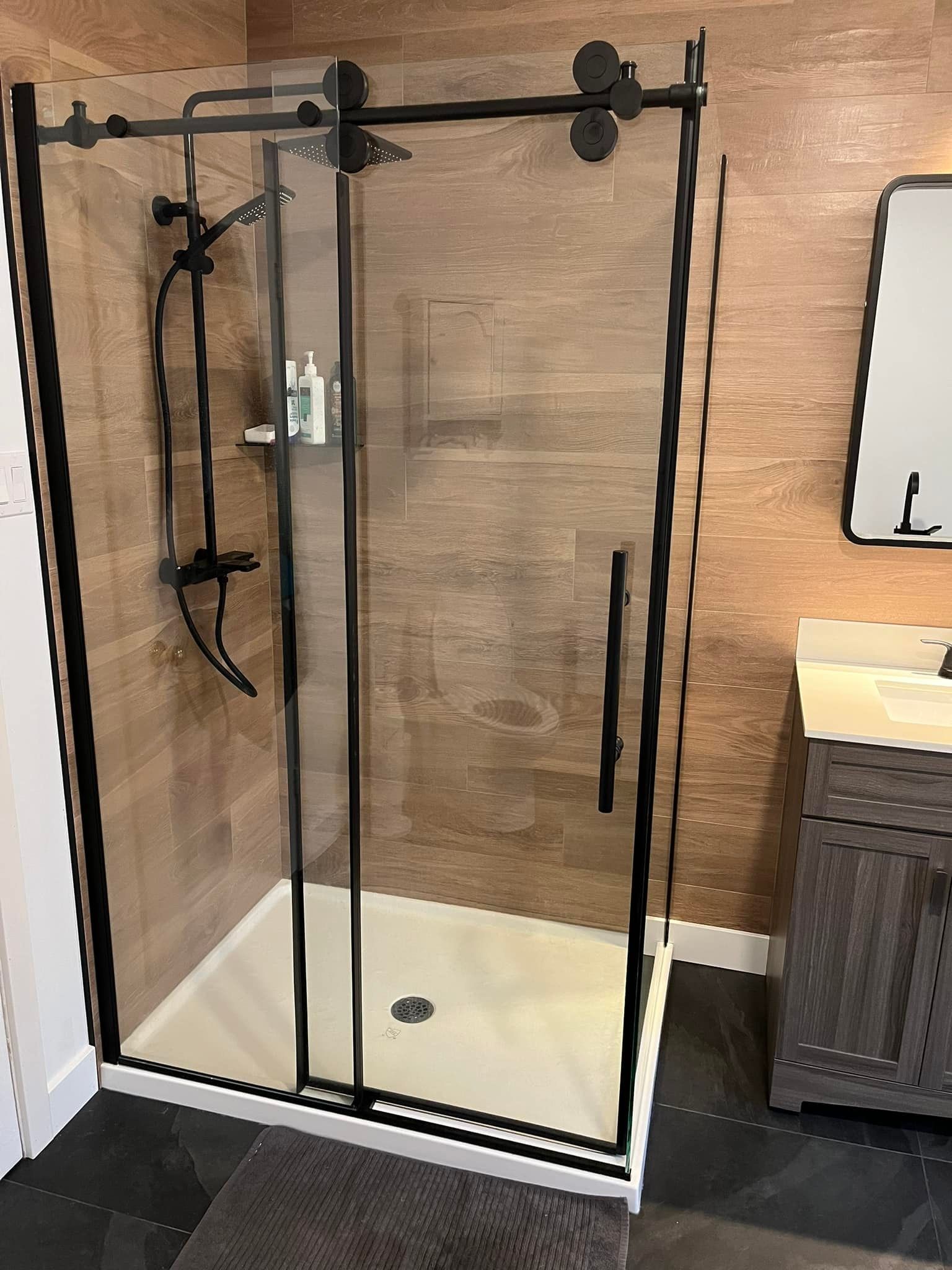 Une salle de bain avec une porte de douche coulissante en verre et un lavabo.