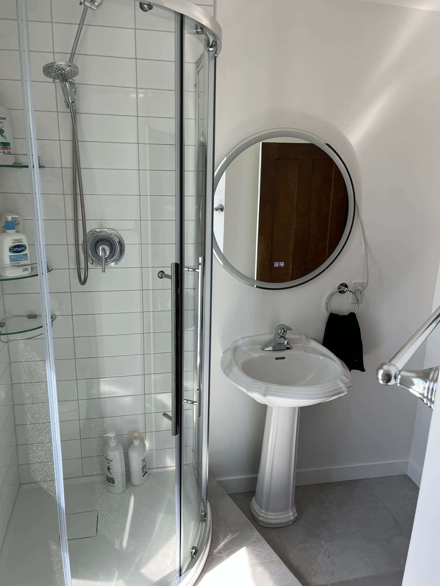 Une salle de bain avec un lavabo, une douche et un miroir.