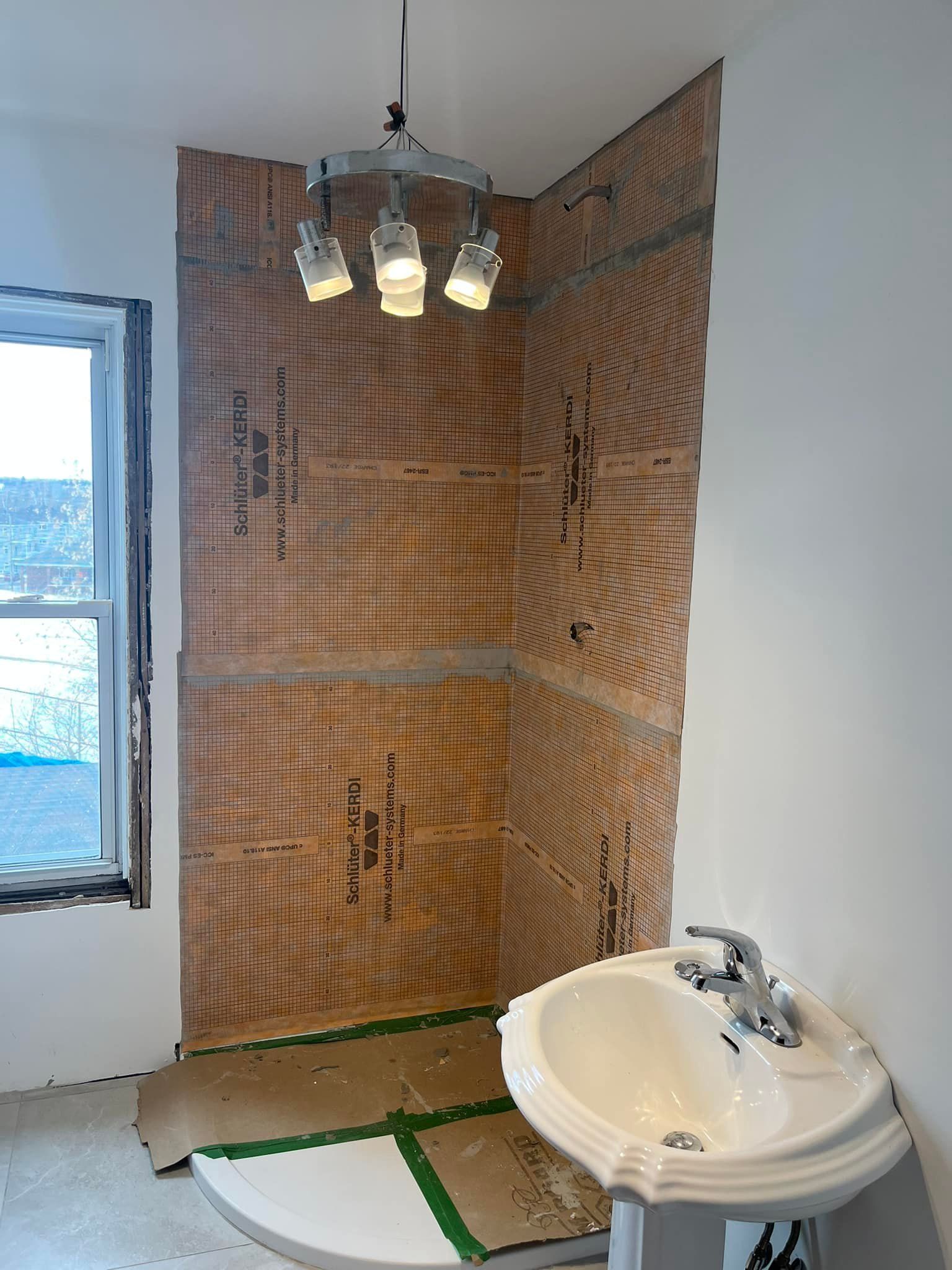 Une salle de bain avec un lavabo et une douche en cours de construction.