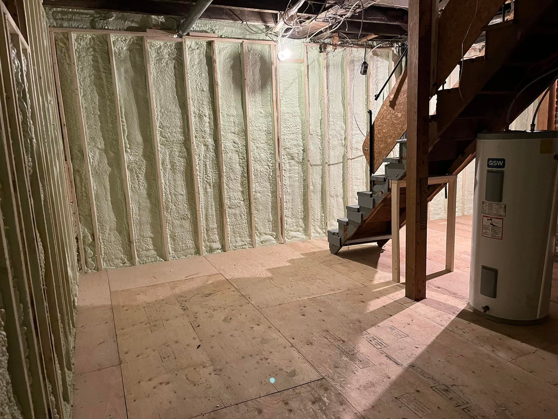 Un sous-sol avec un escalier et un chauffe-eau.